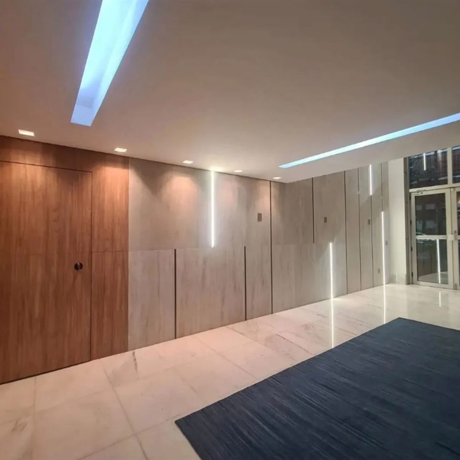 Hall de entrada revestido em mármore e madeira com iluminação linear